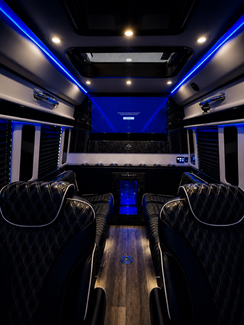 Executive Sprinter cabin with four captain chairs facing a big screen